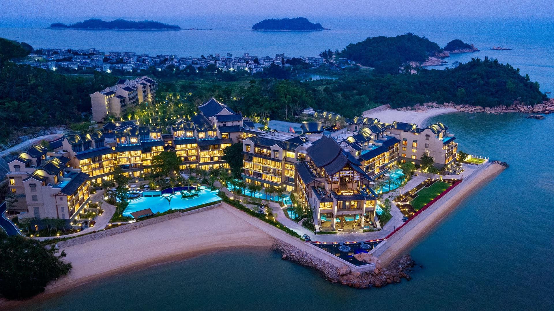 Angsana Zhuhai Phoenix Bay resort illuminated by night, nestled by a serene bay with lush surroundings.