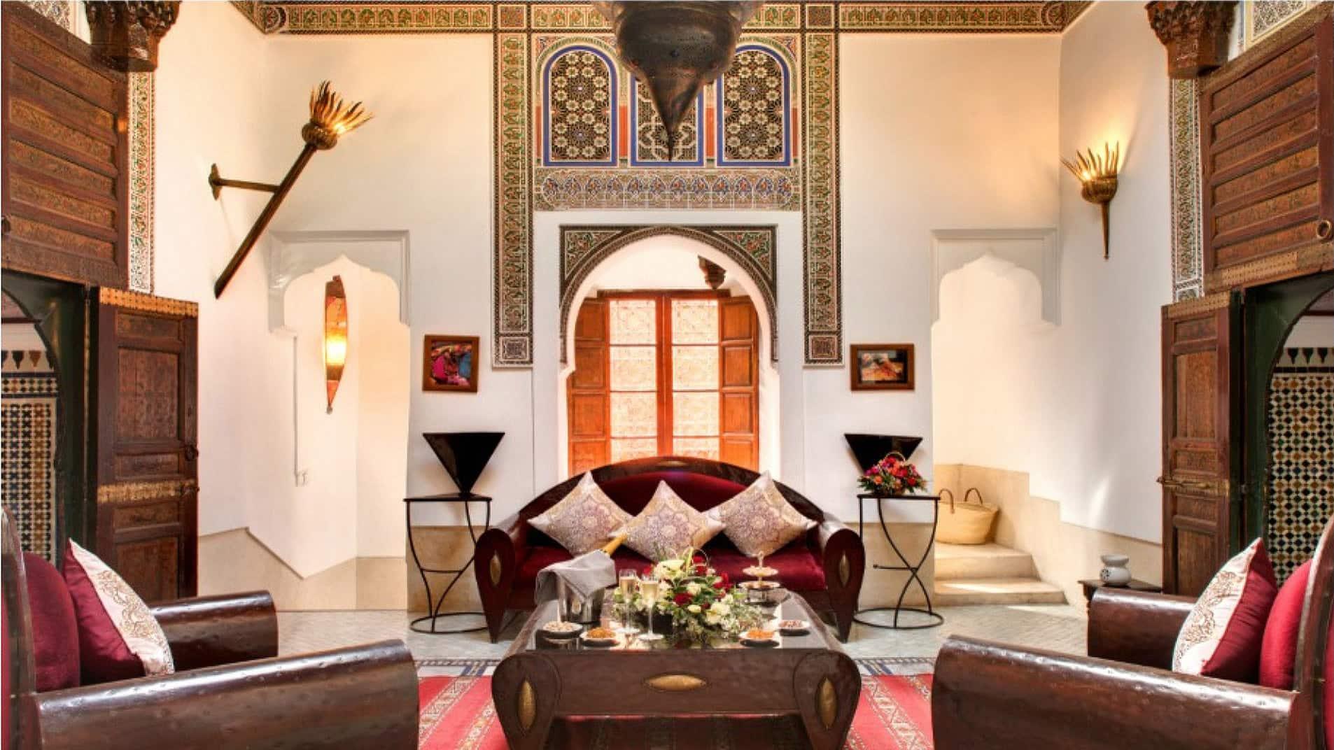 Luxurious lounge with ornate decor, a plush sofa, and a table set for tea in Angsana Riads Collection Marrakech, Riad Si Said.