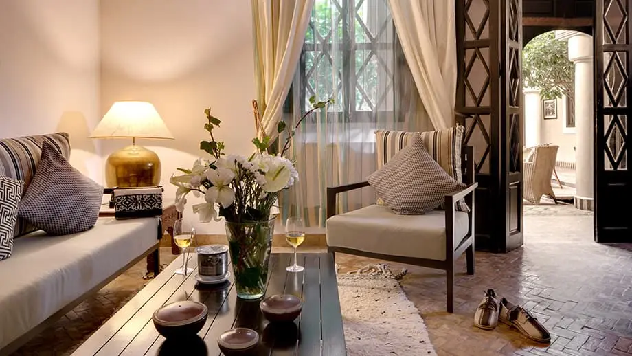 Cozy living area with striped cushions, a flower vase, and warm lighting; Angsana Riads Collection - Marrakech, Zaouia Suite.
