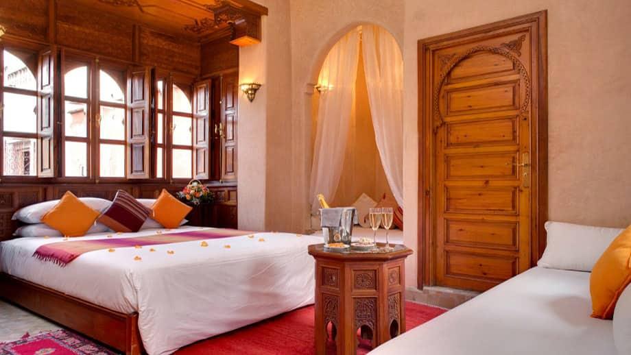 Luxurious bed and couch adorned with pillows in Angsana Riads Collection - Marrakech, Lydines Deluxe King.