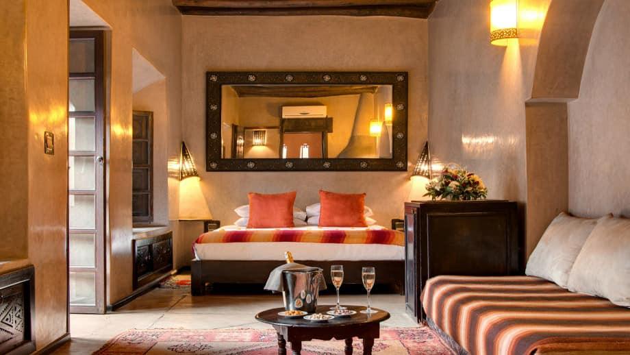Luxurious bedroom with a king bed features striped decor and seating area at Angsana Riads Collection Marrakech, Tiwaline Deluxe King.