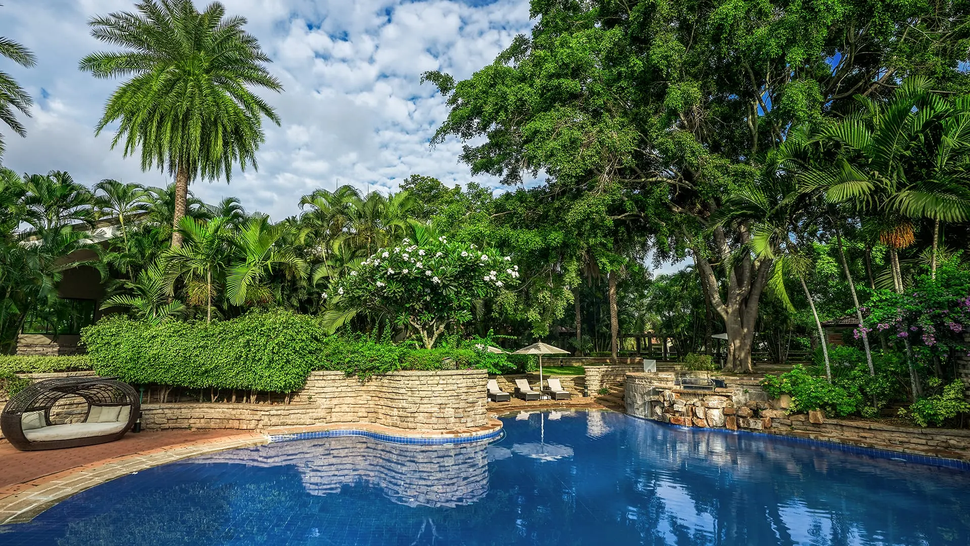 Pool reflecting lush greenery; Angsana Oasis Spa & Resort Bangalore offers serene relaxation.