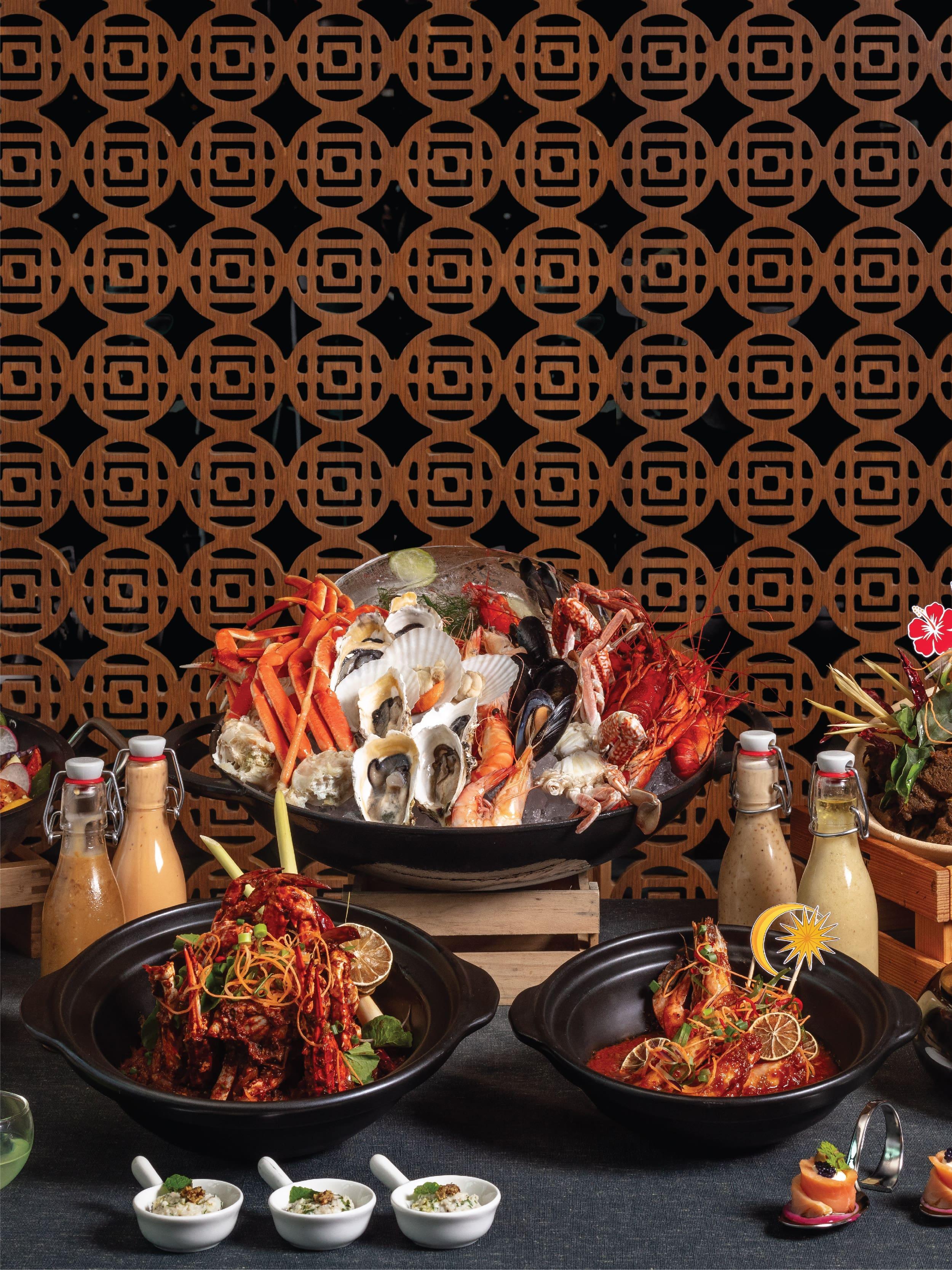 A table topped with plates of seafood and drinks at Jendela restaurant, Angsana Teluk Bahang, Penang