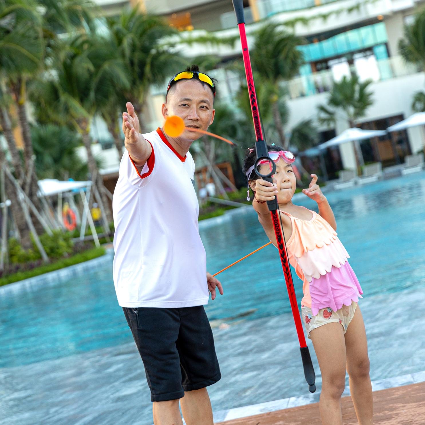 A staff member guiding a child guest in archery.