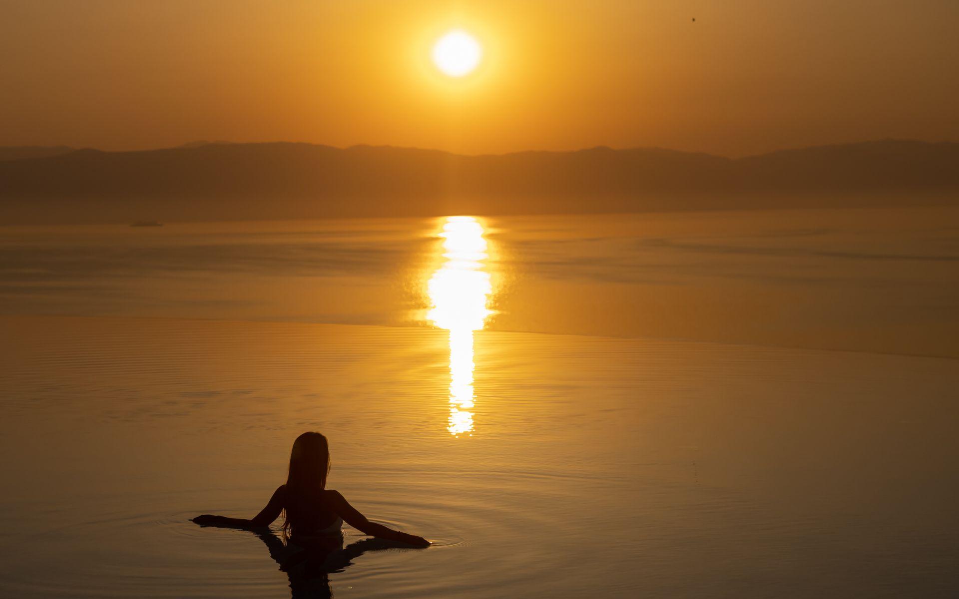 woman in sunrise in infinity pool 