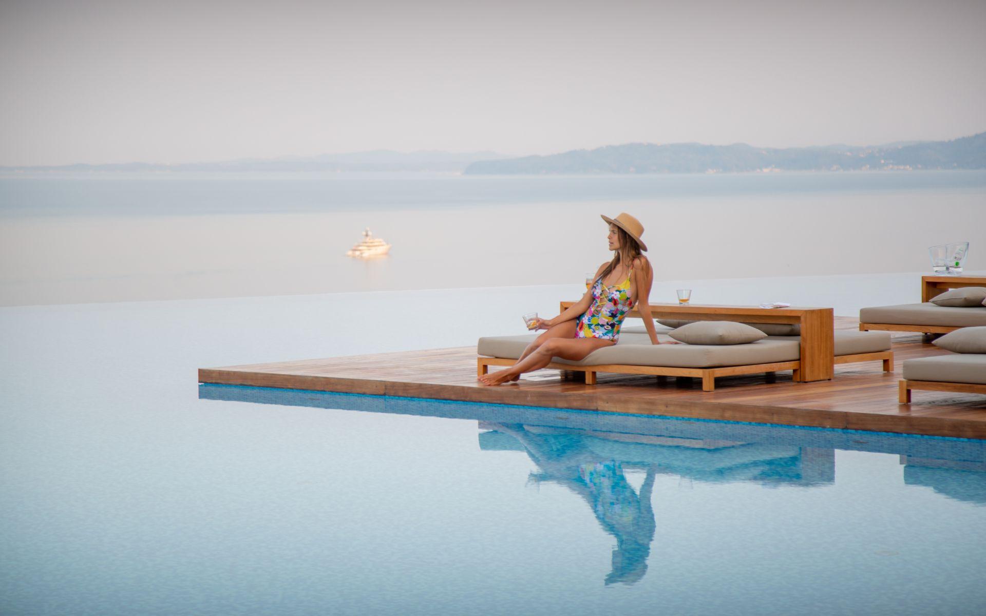woman sitting on the edge of an infinity pool