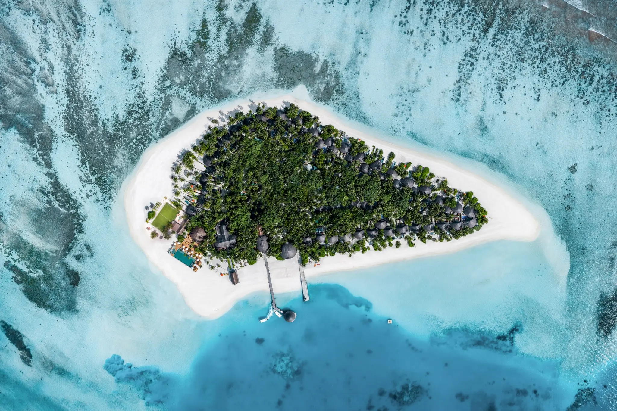 an aerial view of a velavaru island in Maldives in the middle of the ocean.