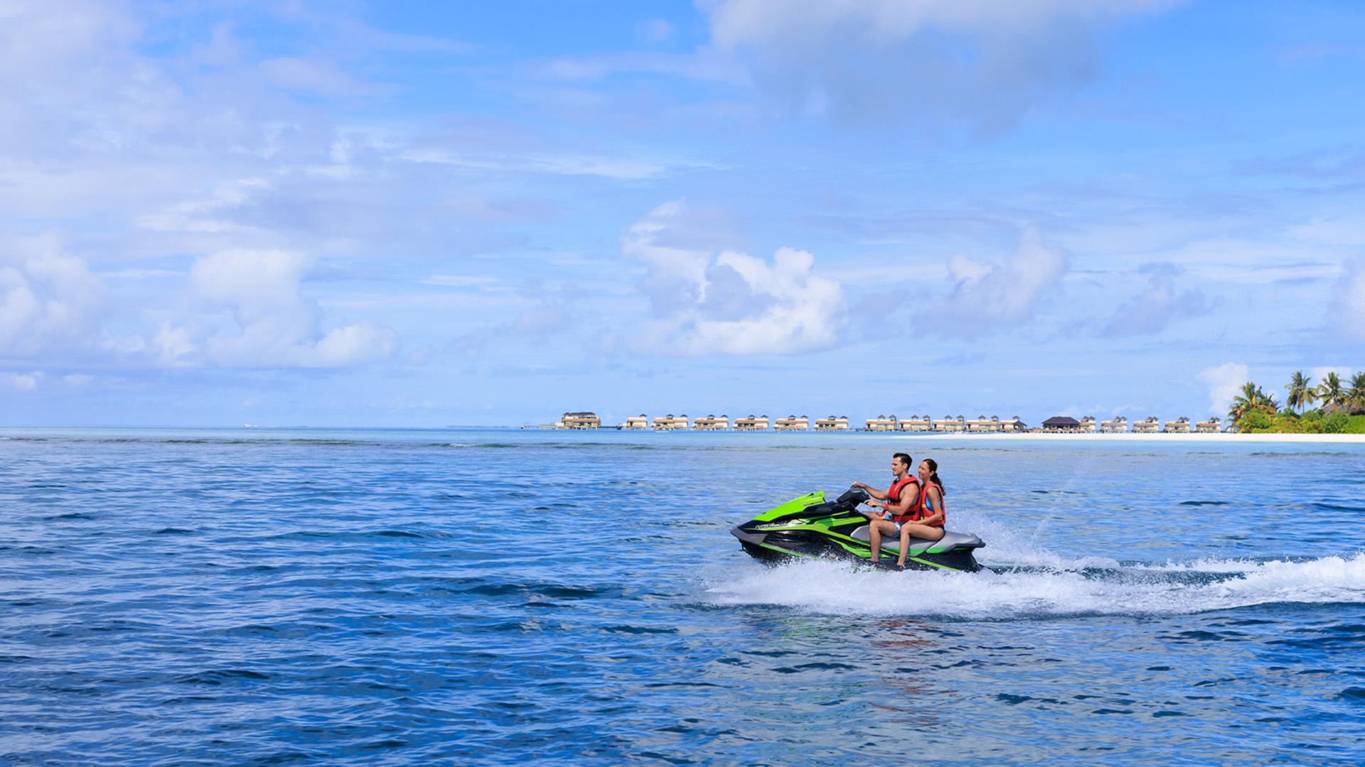 A couple enjoys a thrilling jetski ride across the turquoise waters of Angsana Velavaru in the Maldives.