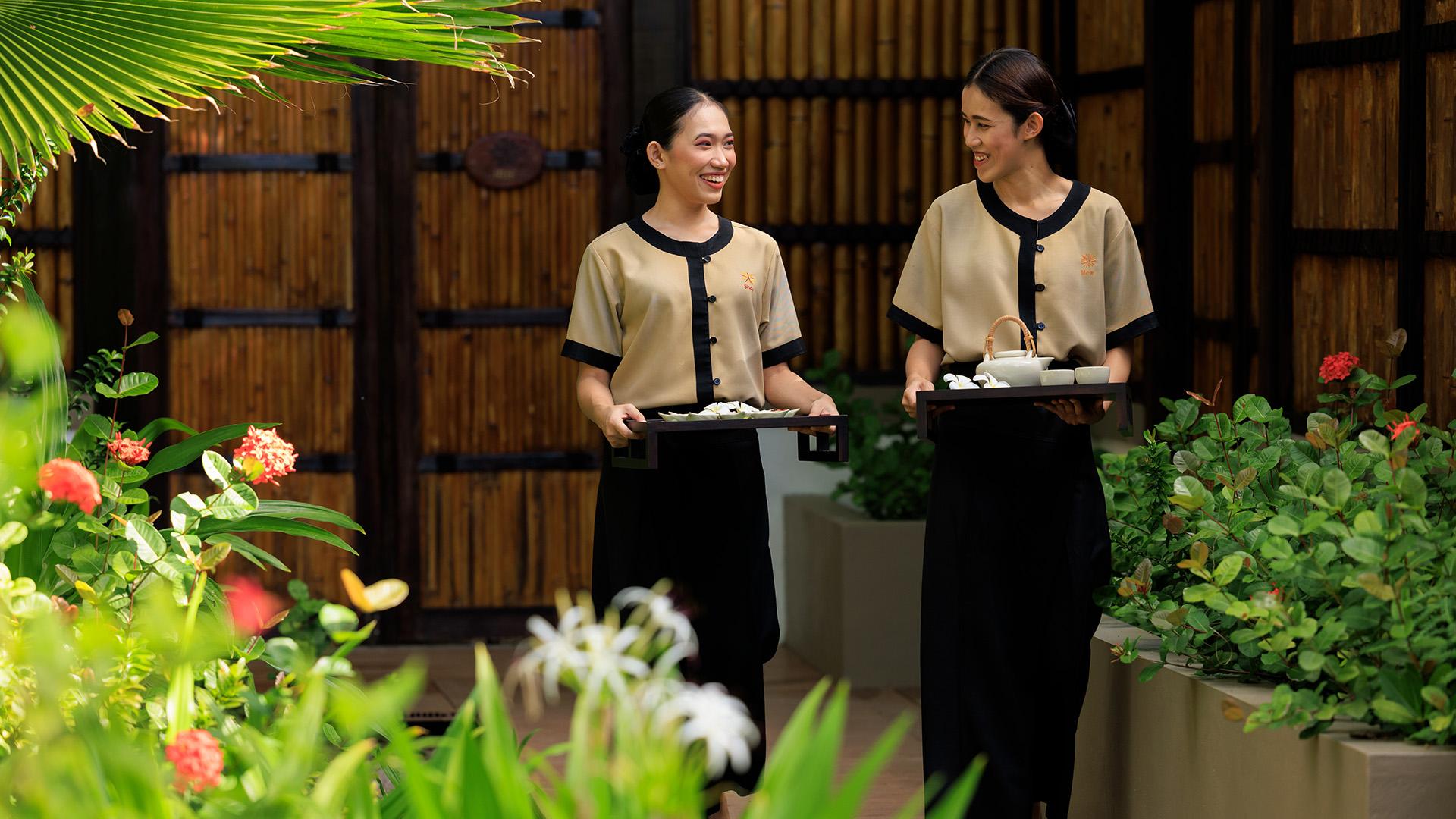 Two Angsana Spa therapists walking side-by-side, ready to pamper guests.