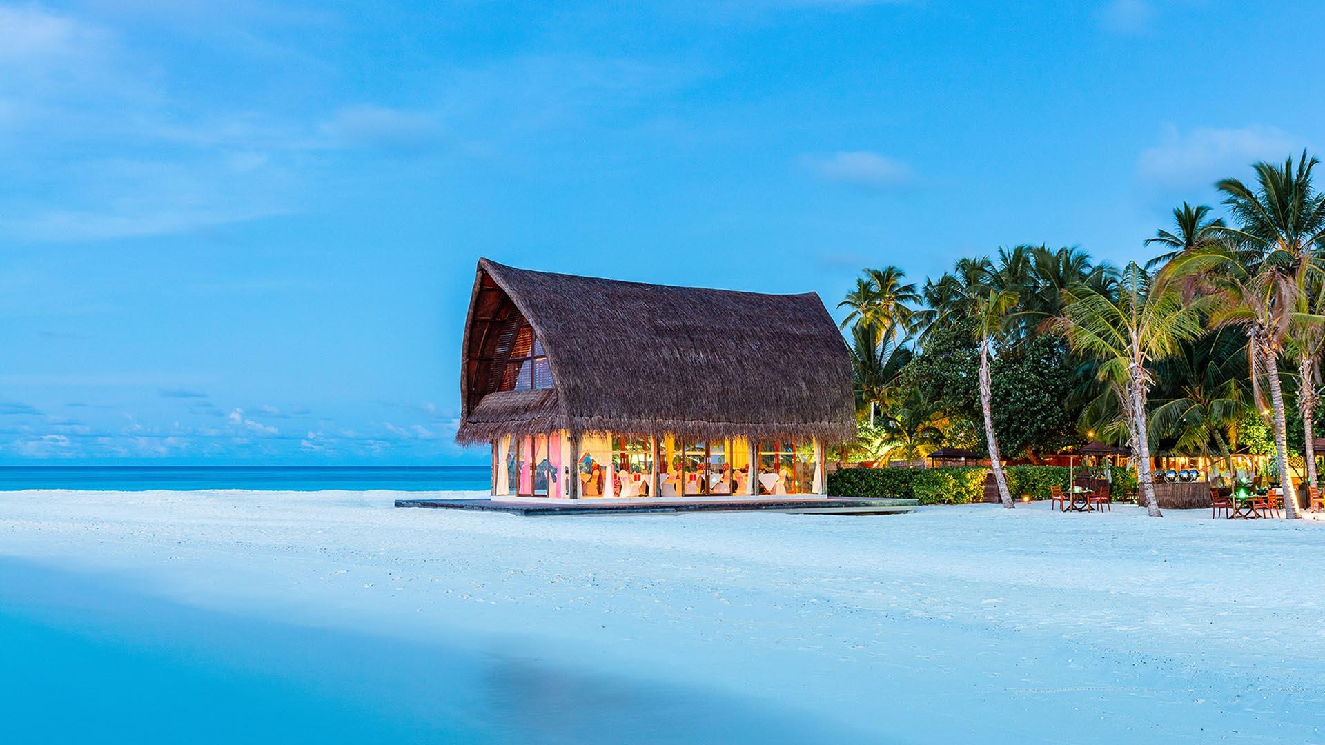 Dreamy beachfront wedding pavilion at Angsana Velavaru, Maldives, bathed in a golden sunset.