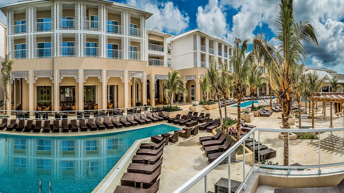 Angsana Cayo Santa Maria resort with poolside lounge chairs, palm trees, and multi-story building.