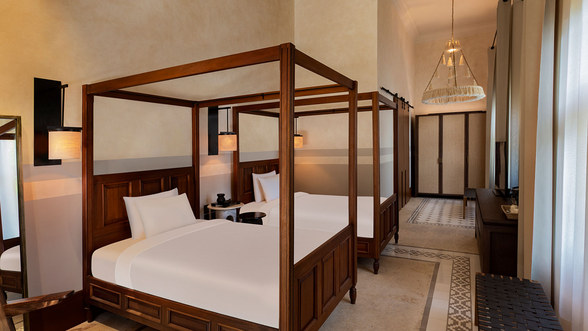Two canopy beds stand symmetrically in a serene, elegant room at Hacienda Xcanatun, Angsana Heritage Collection.