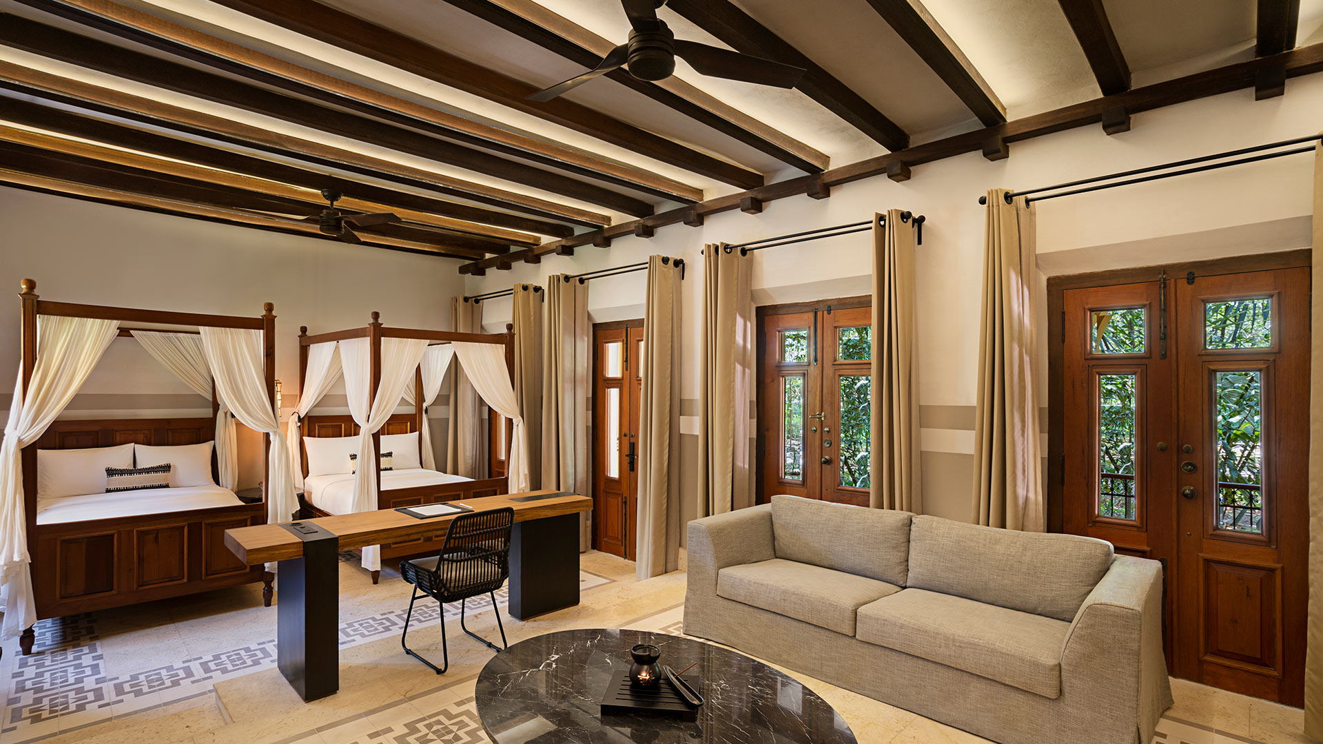Canopy bed adorns a rustic room; sofas and curtains accentuate Hacienda Xcanatun, Angsana Heritage Collection.