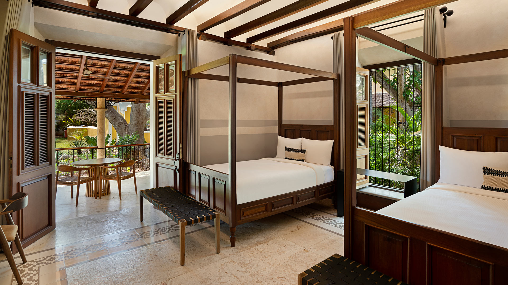 Two wooden canopy beds sit by open doors to a lush patio at Hacienda Xcanatun, Angsana Heritage Collection.