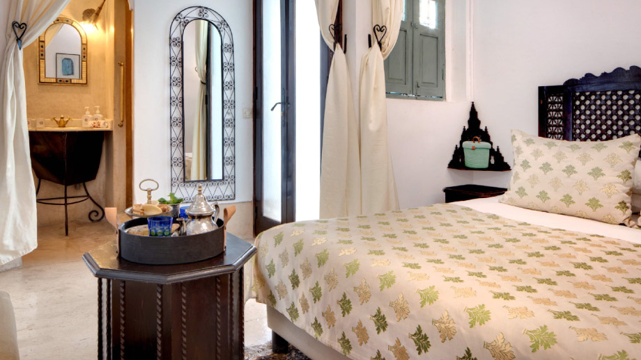 Cozy suite with elegant bed and seating area, featuring Moroccan decor at Angsana Riads Collection - Marrakech, Firdaus Junior Suite.