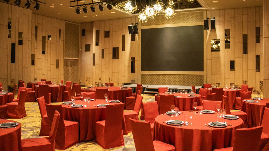 Red-clothed tables set for dining in a warmly lit ballroom at Angsana Teluk Bahang Penang.