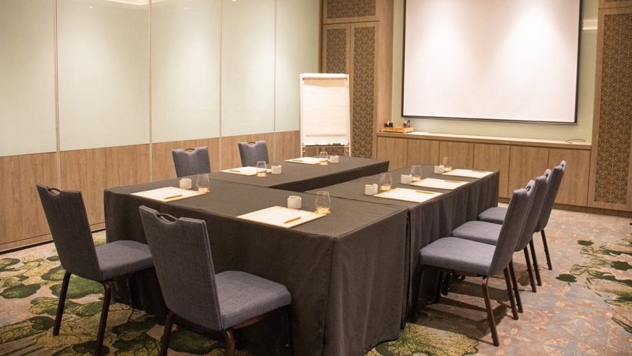 Meeting room with a U-shaped setup featuring blue chairs, a flip chart, and screen at Angsana Teluk Bahang Penang.
