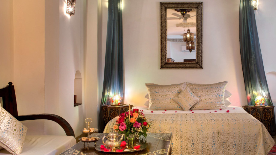 Elegant bed adorned with rose petals, flanked by ornate lamps, in Angsana Riads Collection - Marrakech Blanc Junior Suite.