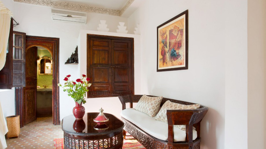 Elegant sofa with cushions beside a dark wooden table and vase in Angsana Riads Collection - Marrakech Blanc Studio King.