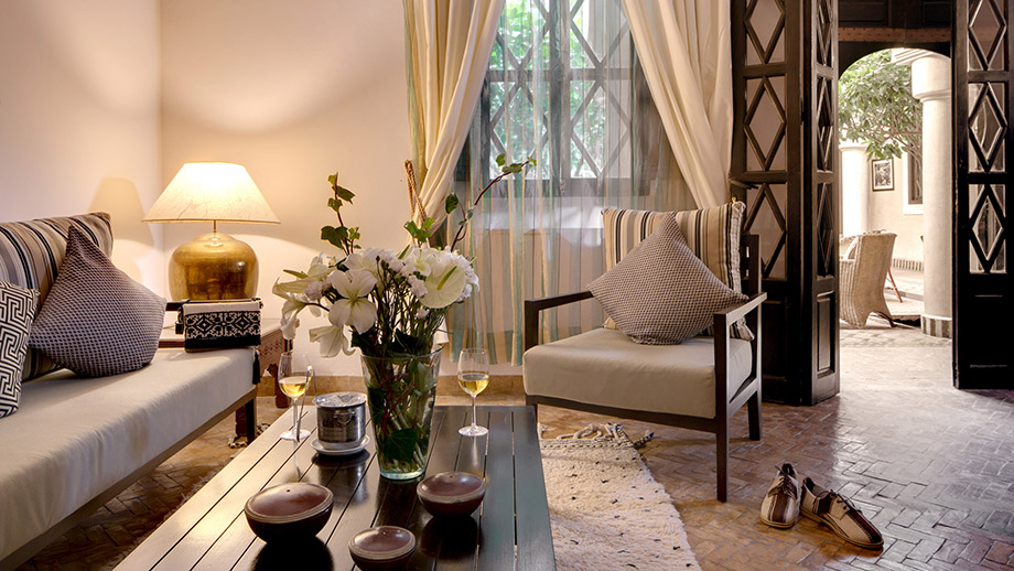 Cozy living area with striped cushions, a flower vase, and warm lighting; Angsana Riads Collection - Marrakech, Zaouia Suite.