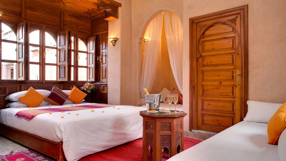 Luxurious bed and couch adorned with pillows in Angsana Riads Collection - Marrakech, Lydines Deluxe King.