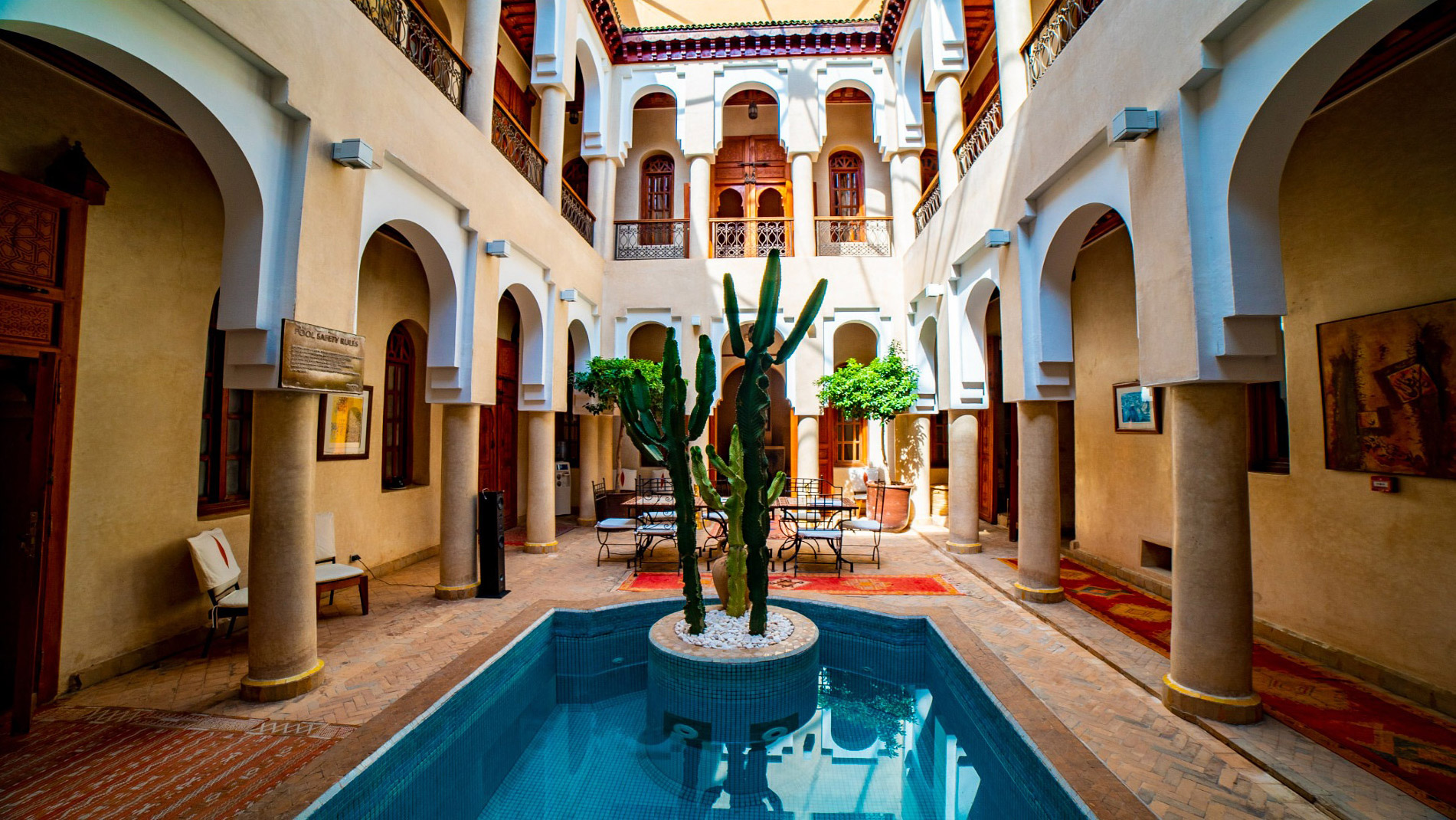 Cactus stands in a courtyard pool, surrounded by arches at Angsana Riads Collection - Marrakech, Riad Lydines.