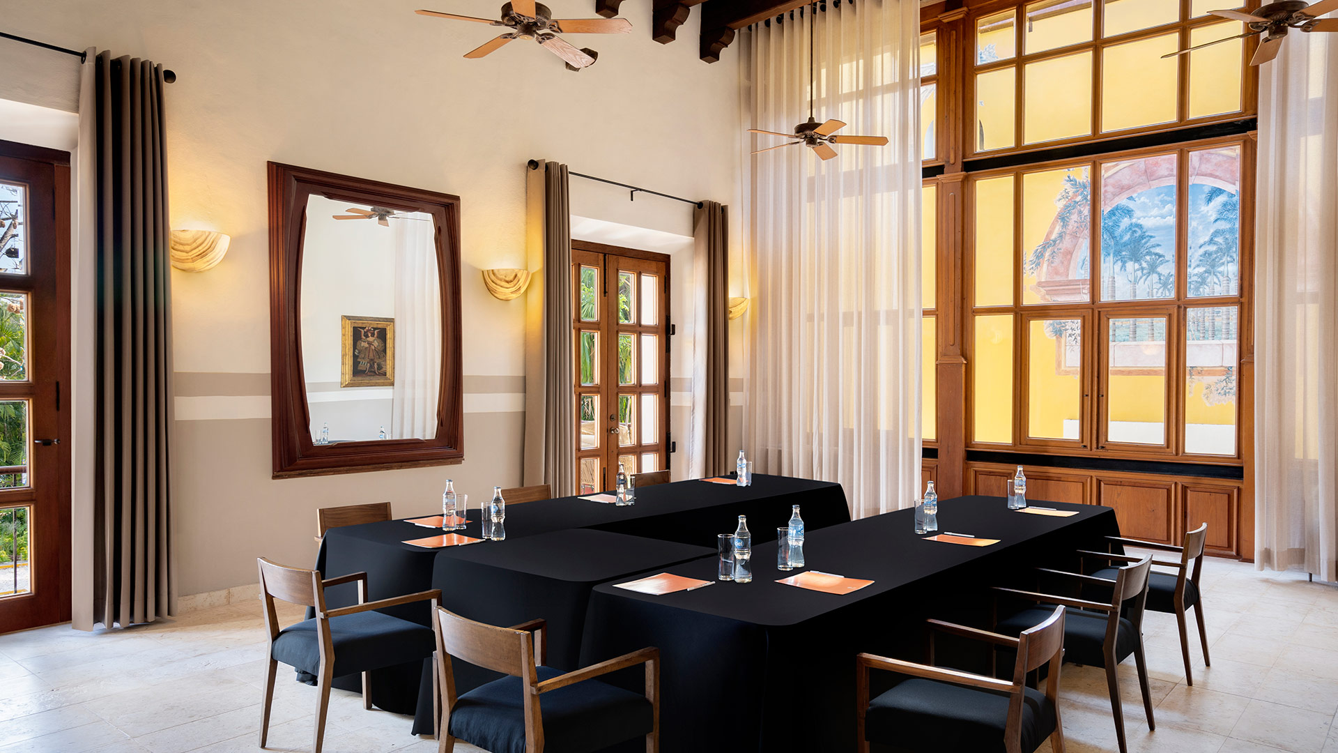 Meeting room features black-covered tables and chairs, set in elegant, sunlit space at Hacienda Xcanatun, Angsana Heritage Collection.
