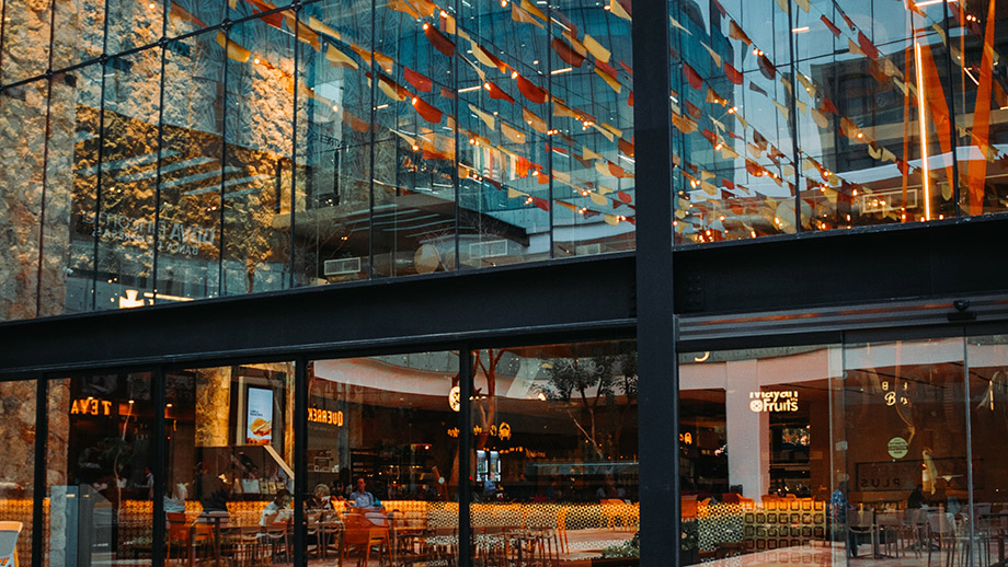 Reflective glass wall showcasing vibrant hanging decor; bustling interiors of Hacienda Xcanatun, Angsana Heritage Collection.