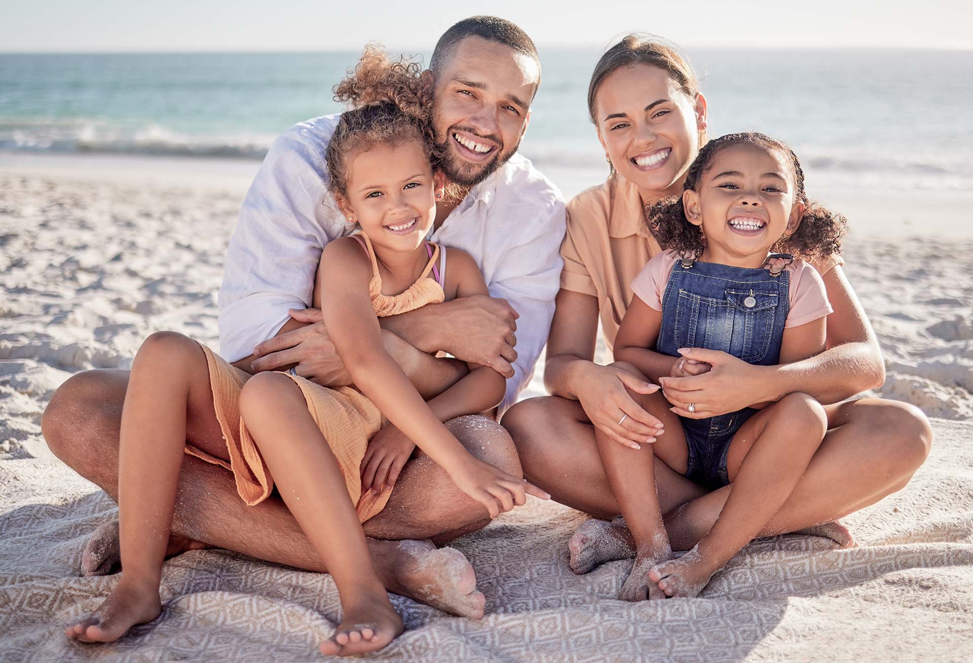 Parents embrace their children on a Maldivian beach at Angsana Velavaru resort