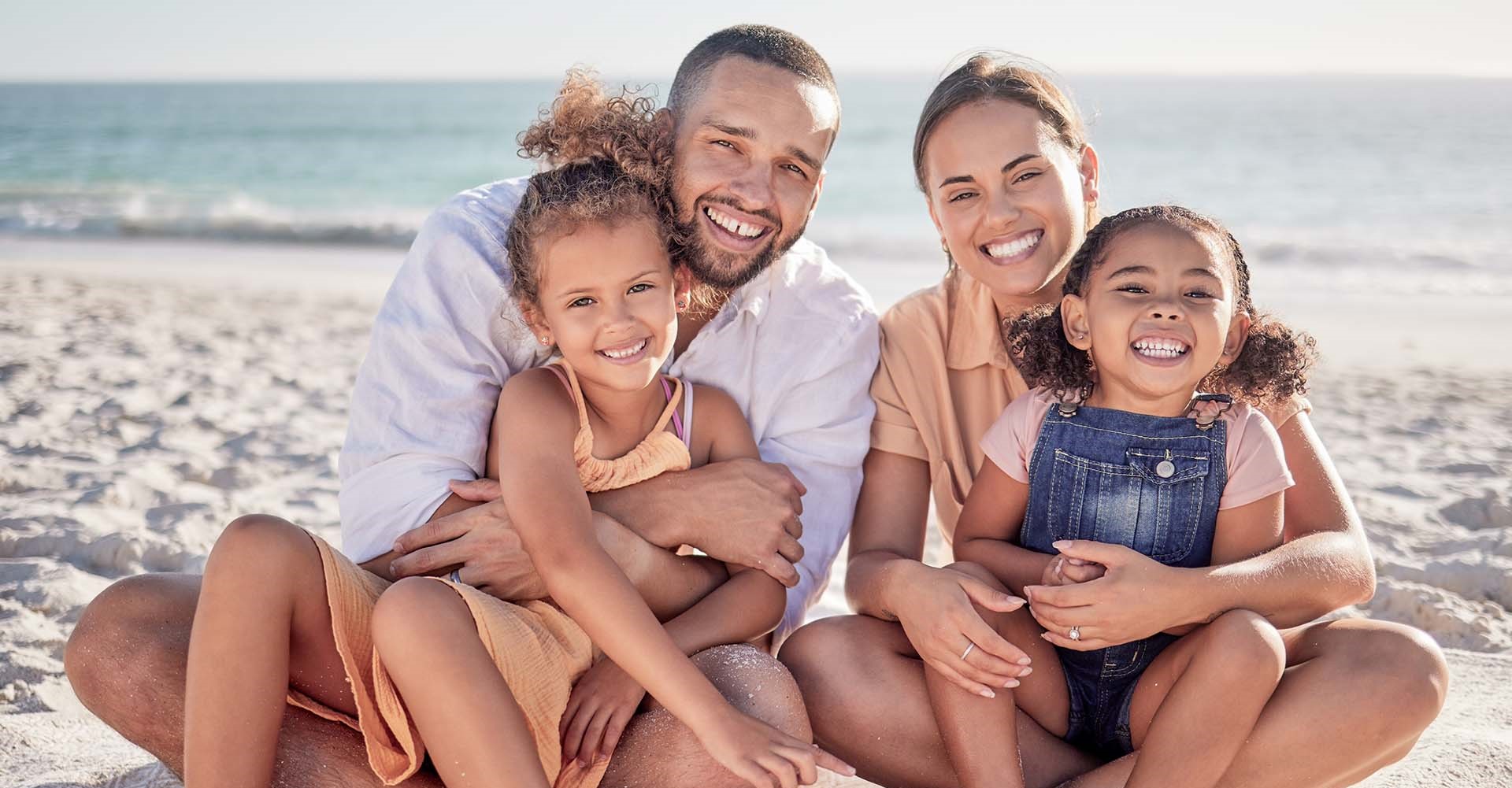 Parents embrace their children on a Maldivian beach at Angsana Velavaru resort.