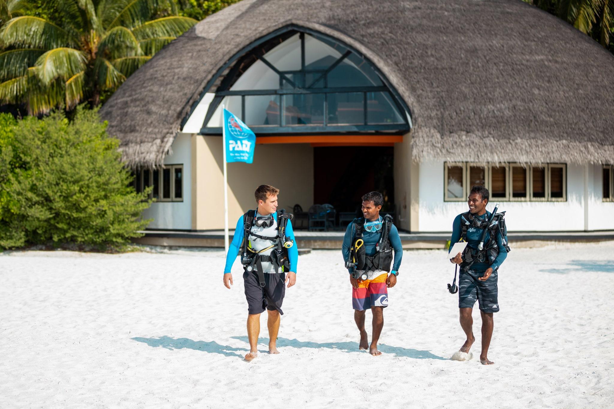 a group of young men standing on top of a sandy beach in Velavaru, Maldives