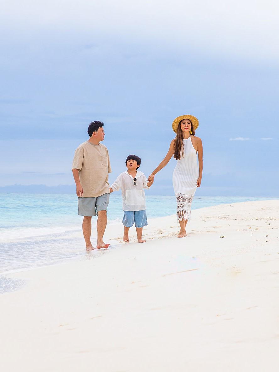 Creating memories in paradise: A happy family strolls along a beautiful beach in the Maldives.